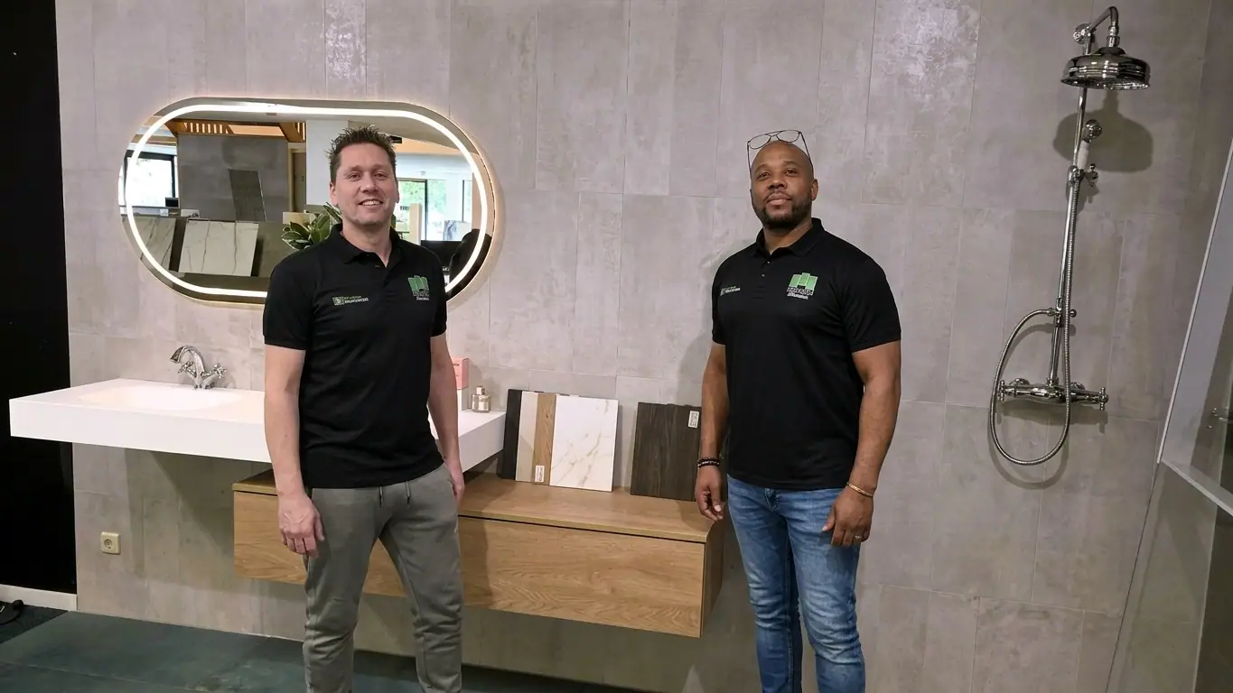 Twee medewerkers van MIJS Tegels & Sanitair in de showroom bij de badkamerdisplay in Zwaag