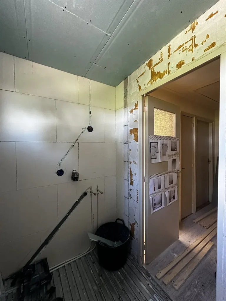 Badkamer gestript met leidingen en inbouwreservoir tijdens de verbouwing (Badkamer tijdens de verbouwing) (badkamer verbouwing)