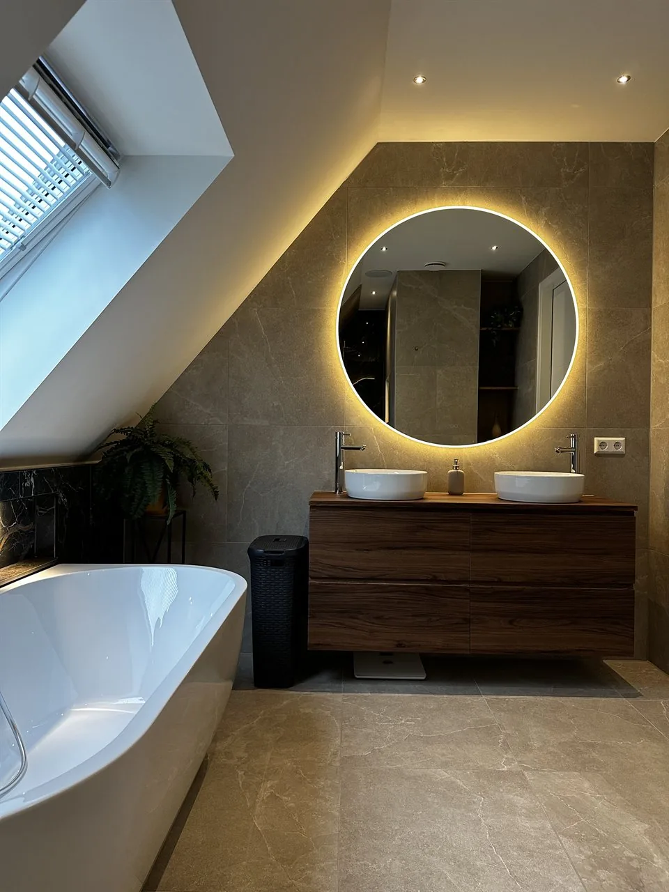 Badkamer met vrijstaand bad en dubbele wastafel onder schuin dak (Badkamer met marmerlook tegels)