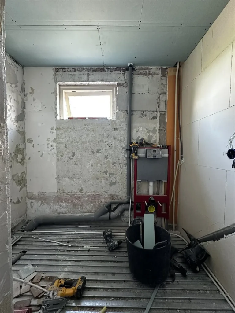Badkamer verbouwing met kale muren en vloerleidingen (Badkamer tijdens de verbouwing)