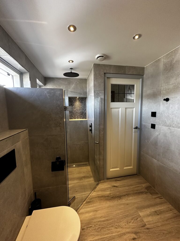 Badkamer met inloopdouche, hangend toilet en houtlook vloer