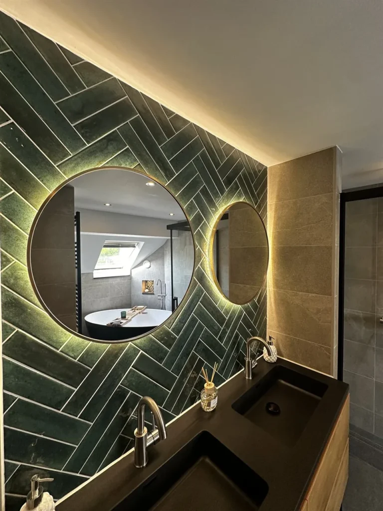 Dubbele wastafel met groene visgraattegels en verlichte ronde spiegel (Luxe badkamer met groene tegels)