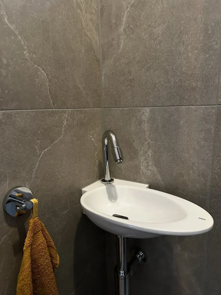 Fonteintje in grijze tegels met gele handdoek (Badkamer met marmerlook tegels)