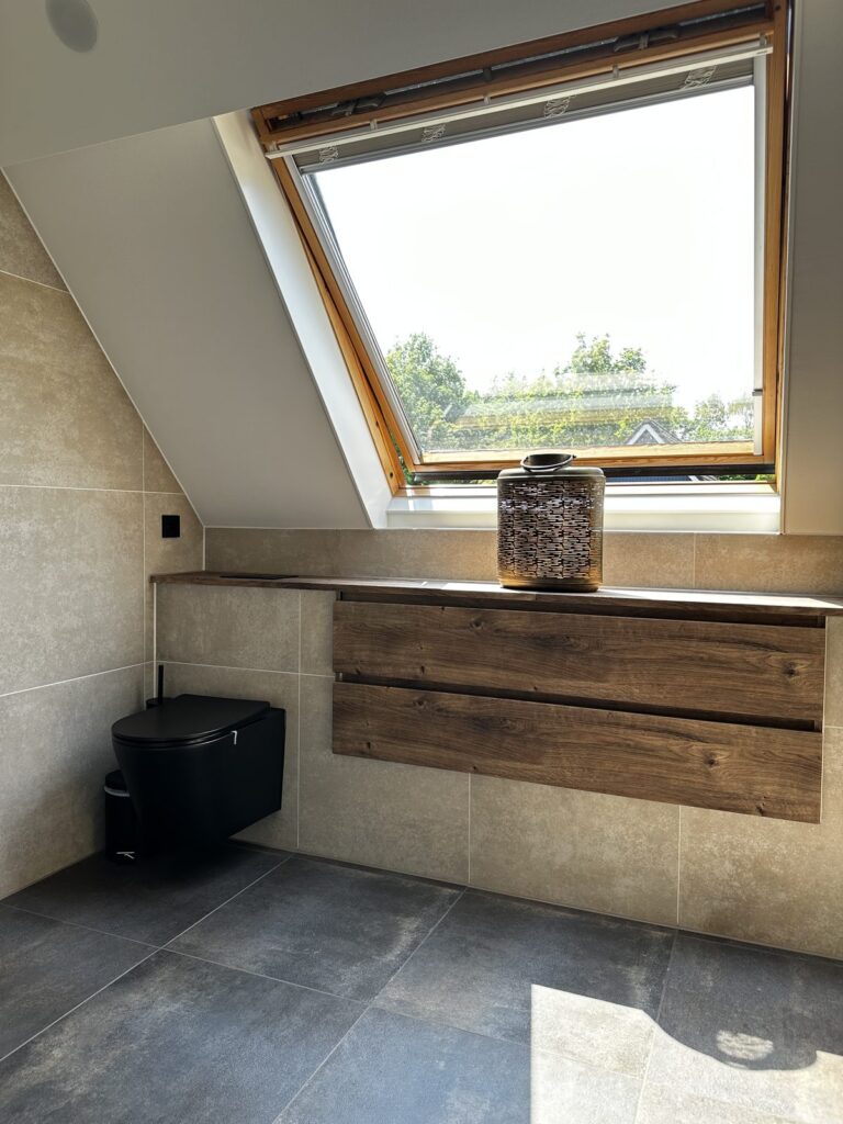 Zwart hangend toilet en badmeubel onder het dakraam