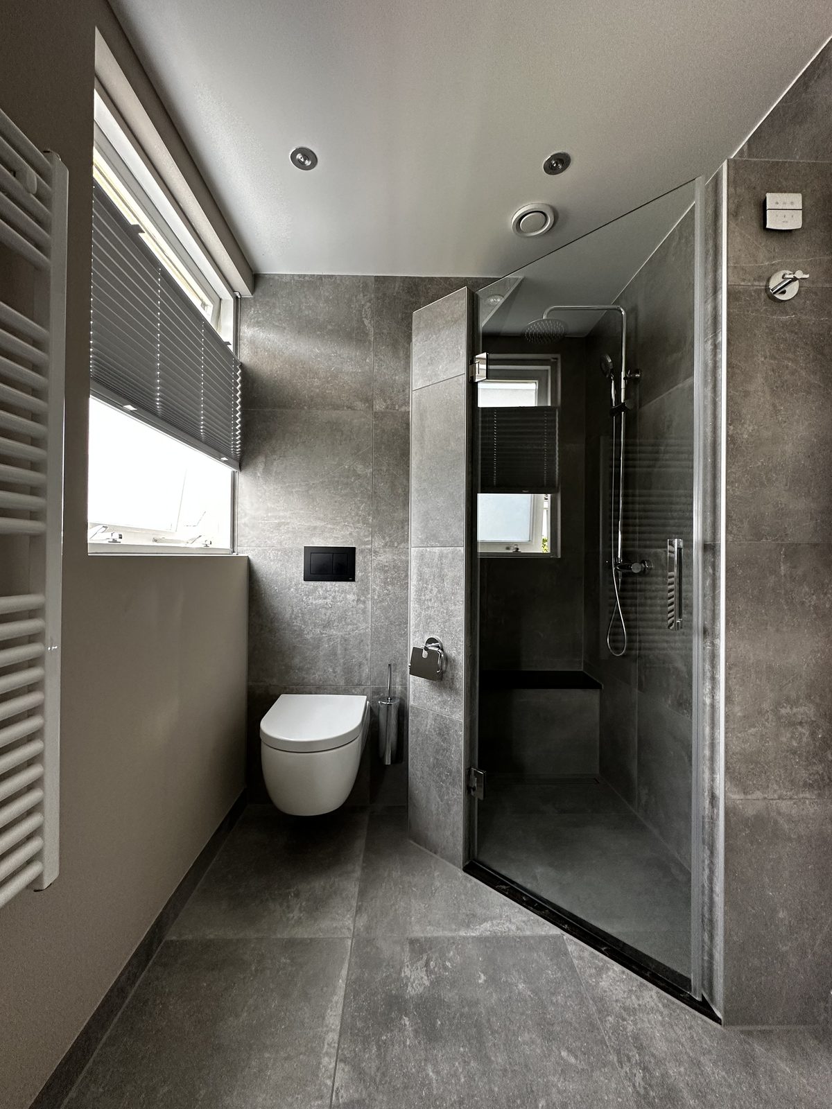 Badkamer met inloopdouche, hangend toilet en betonlook tegels