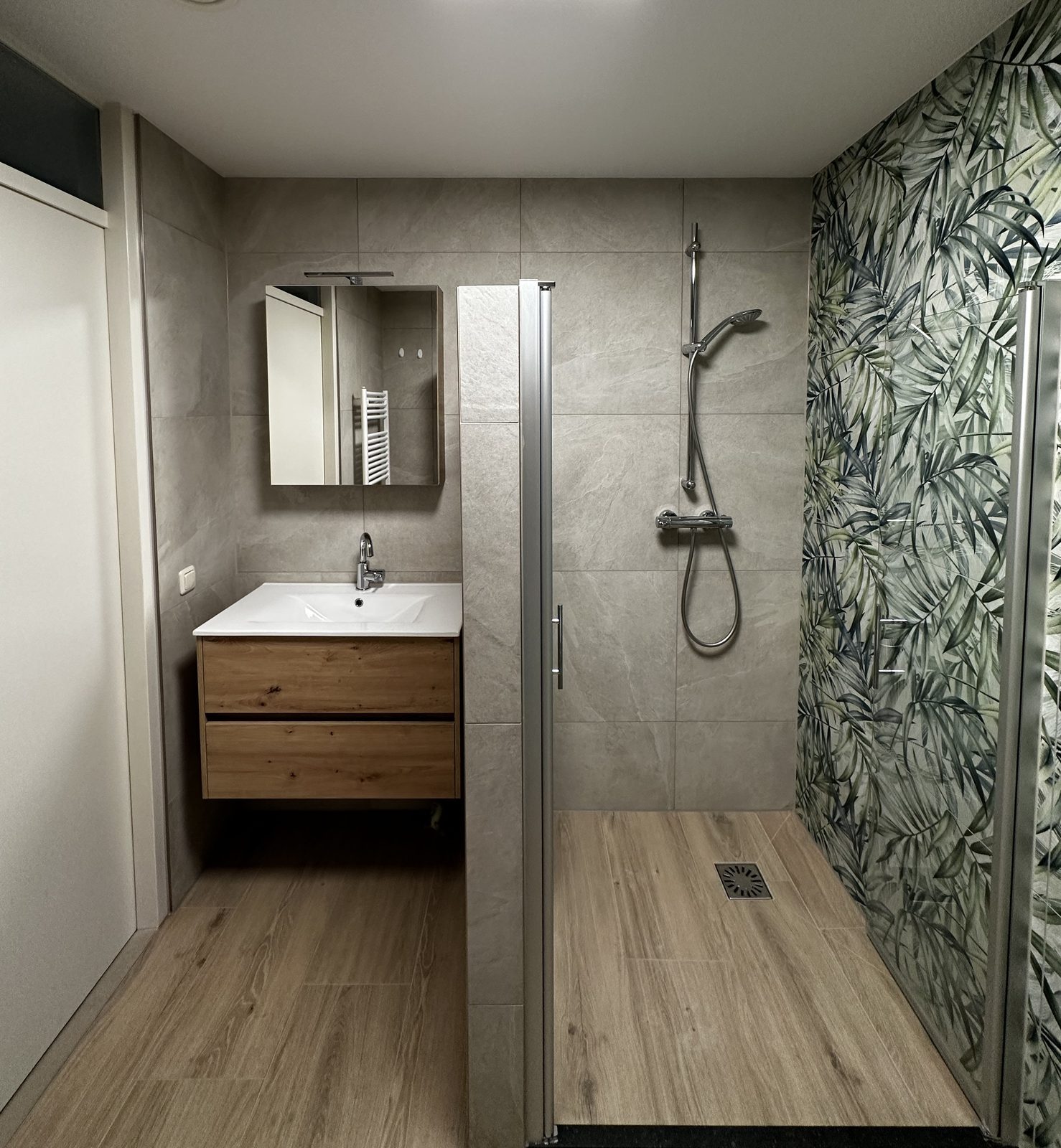 Moderne badkamer met eiken badmeubel, grijze steenlook wandtegels, houtlook vloer en inloopdouche