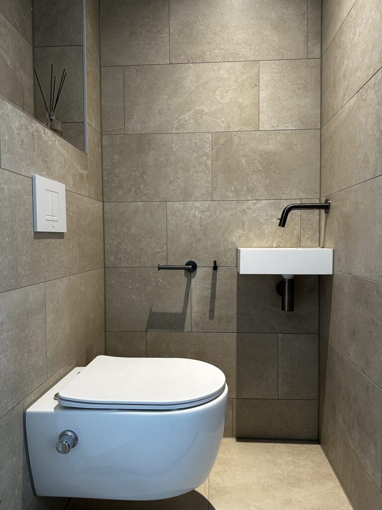 Toilet met zwarte kraan en natuursteenlook tegels