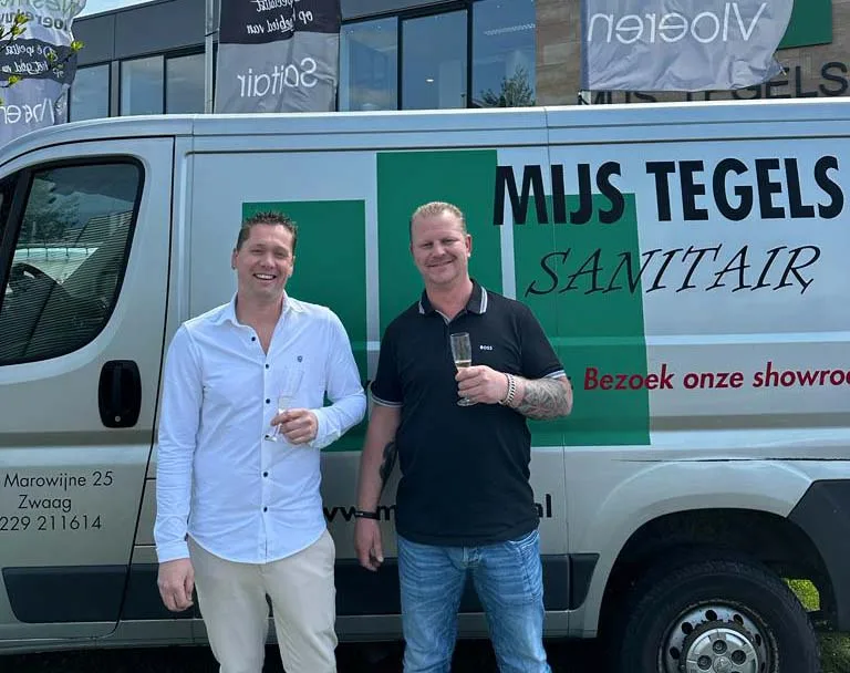 Twee eigenaren van MIJS Tegels & Sanitair met een glas voor de bedrijfsbus, op het moment van de overname