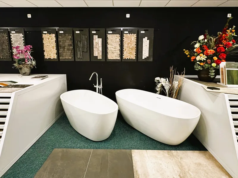Twee vrijstaande baden voor een wand met mozaïektegelstalen in de showroom van MIJS Tegels & Sanitair in Zwaag