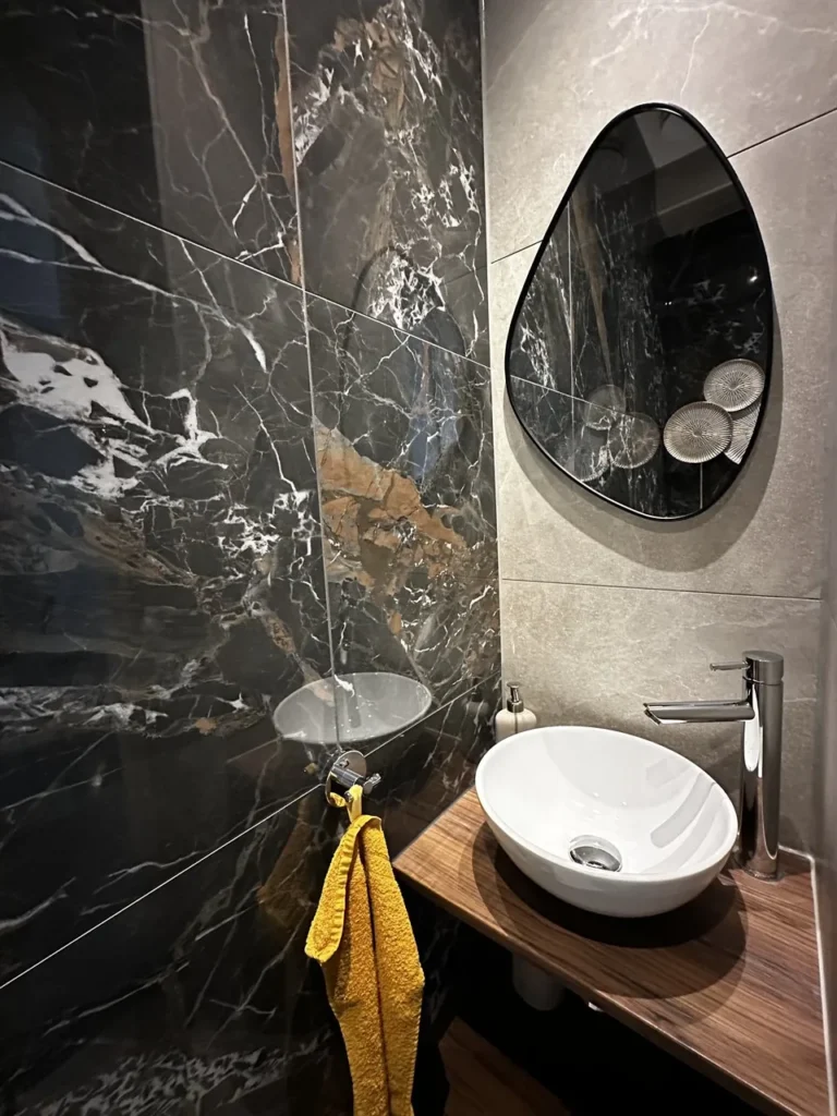 Toilet met opbouwwastafel en organische spiegel (Badkamer met marmerlook tegels)