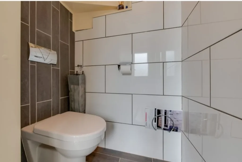 Toilet voor de renovatie met witte wandtegels (Badkamer renovatie met 3D-ontwerp)