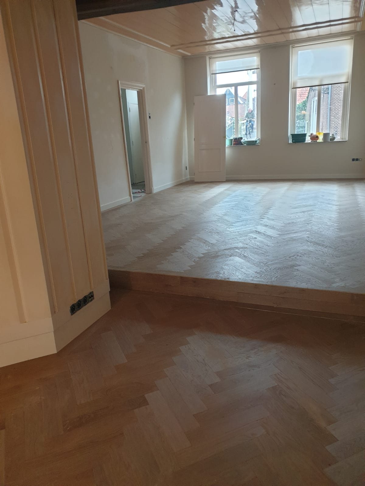 Ruime kamer met visgraat parketvloer en grote ramen