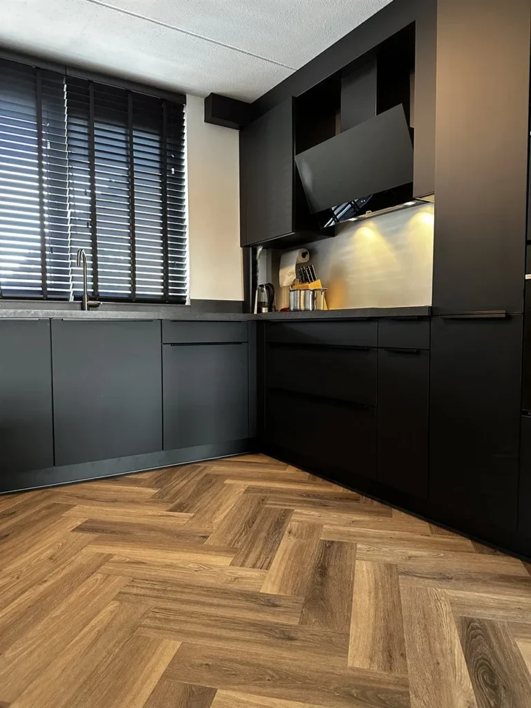 Visgraatvloer houtlook in woonkeuken met zwarte keuken (Trap en visgraatvloer houtlook)