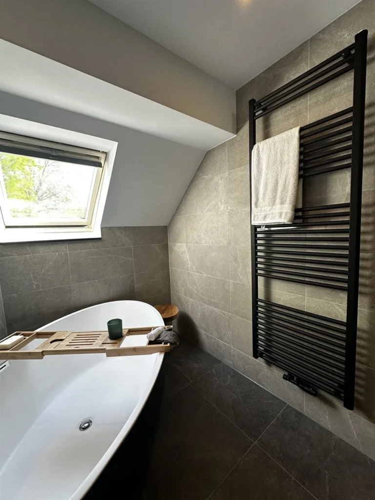 Vrijstaand bad en zwarte designradiator onder dakraam (Luxe badkamer met groene tegels)