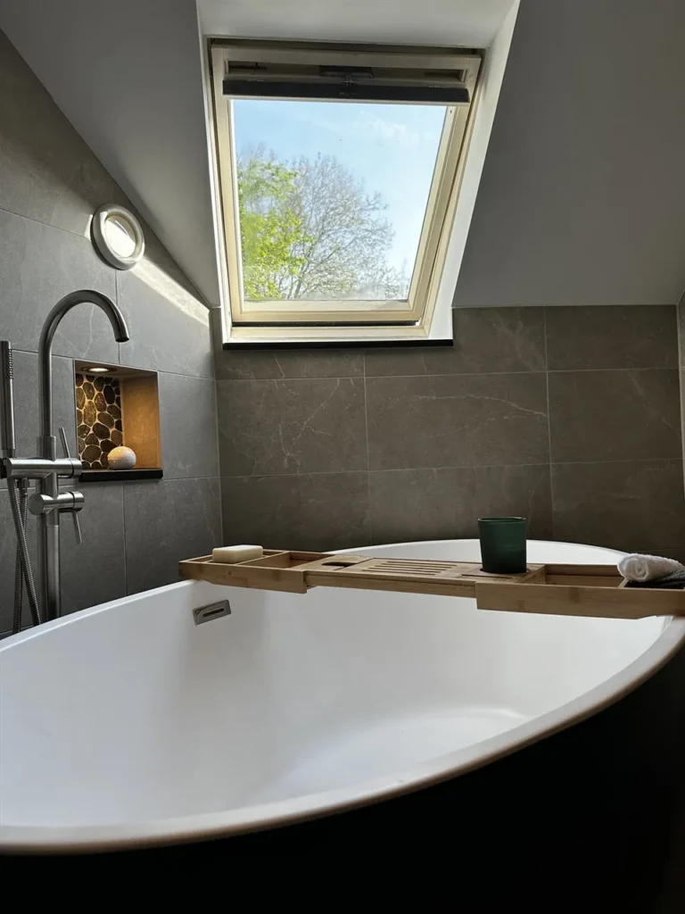 Vrijstaand zwart bad onder dakraam in luxe badkamer (Luxe badkamer met groene tegels)