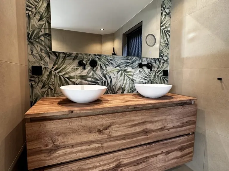 Opgeleverde badkamer met eiken badmeubel, twee waskommen en een botanische wand, gerealiseerd door MIJS Tegels & Sanitair